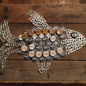 May include: A wooden board with a fish design made from silver bottle caps and Corona beer bottle caps. The fish has a black and white design with the words "Corona Extra" on the bottle caps.