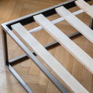 May include: A metal bed frame with wooden slats. The frame is silver and the slats are a light wood color.