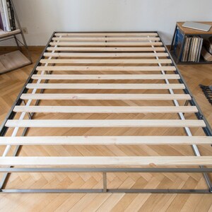 May include: A metal bed frame with a slatted wooden base. The frame is silver and the slats are light wood.