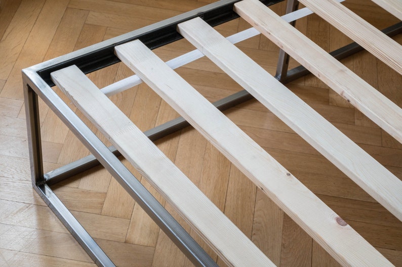 May include: A metal bed frame with wooden slats. The frame is silver and the slats are a light wood color.