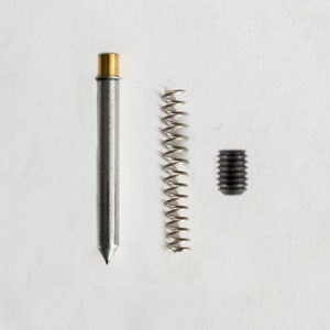 May include: A silver metal pen with a gold top, a silver metal spring, and a black metal screw.