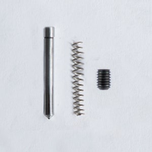 May include: A silver metal rod with a pointed tip, a silver spring coil, and a black metal screw.