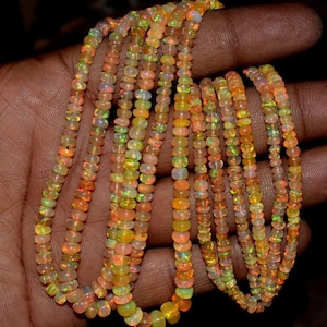 May include: Several strands of opal bead necklaces. The beads are a mix of orange, yellow, and green hues, with a subtle iridescence. The beads are small and round, strung together to form multiple necklaces.
