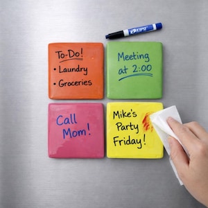 May include: Four colorful square magnetic dry-erase boards with handwritten notes attached to a stainless steel refrigerator. The notes include "To-Do!", "Meeting at 2:00", "Call Mom!", and "Mike's Party Friday!". A blue marker and a wipe are also present.