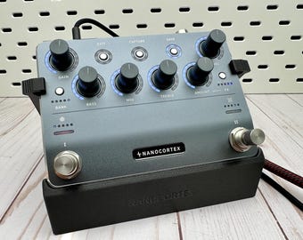 May include: A gray Nano Cortex guitar effects processor mounted on a black stand. The device features five black rotary knobs labeled Gain, Bass, Mid, Treble, and Amount, with blue LED rings. It includes two silver footswitches, labeled I and II, and various buttons for Exit, Capture, and Save functions.