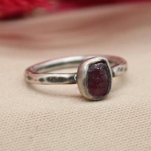 May include: A silver ring with a hammered band and a deep red gemstone set in a bezel setting.