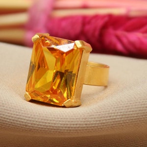 May include: A gold ring with a large, rectangular, yellow gemstone.