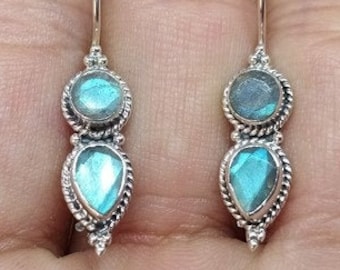 May include: A pair of silver dangle earrings with two teardrop-shaped blue labradorite stones.