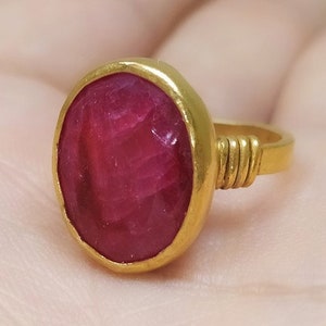 May include: A gold ring with a large, oval-shaped, red gemstone.