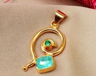 May include: A gold pendant featuring a blue and green gemstone. The pendant is shaped like a swirl.
