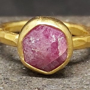 Op de afbeelding: Een gouden ring met een roze edelsteen gezet in een gehamerde gouden zetting.