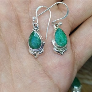 Pu&ograve; includere: Un paio di orecchini pendenti in argento con pietre preziose verdi a forma di pera. Gli orecchini hanno una montatura in argento dettagliata e ornata e una classica chiusura a gancio. Le pietre preziose sono il punto focale, mostrando una ricca tonalit&agrave; smeraldo.