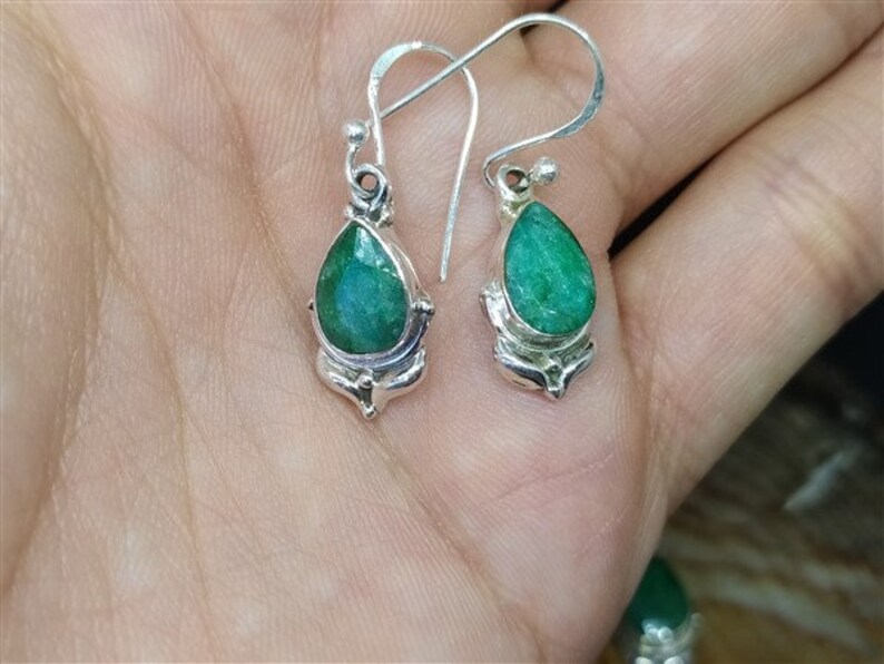 Pu&ograve; includere: Un paio di orecchini pendenti in argento con pietre preziose verdi a forma di pera. Gli orecchini hanno una montatura in argento dettagliata e ornata e una classica chiusura a gancio. Le pietre preziose sono il punto focale, mostrando una ricca tonalit&agrave; smeraldo.