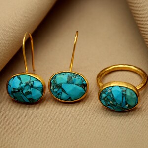 May include: A set of gold earrings and a ring with turquoise stones. The earrings have a drop design and the ring is a simple band.