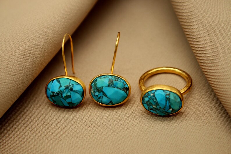 May include: A set of gold earrings and a ring with turquoise stones. The earrings have a drop design and the ring is a simple band.