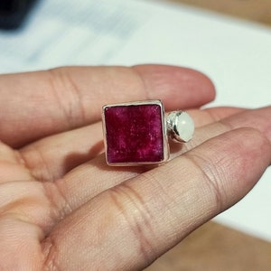 K&ouml;nnte beinhalten: Ein silberner Ring mit einem quadratischen roten Edelstein und einem kleineren wei&szlig;en Edelstein.