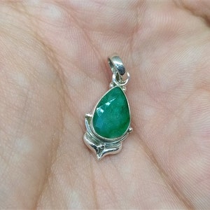 Pu&ograve; includere: Ciondolo in argento con una pietra preziosa verde smeraldo sfaccettata a forma di pera. Il ciondolo ha un'incastonatura decorativa in argento e un'asola per una catena. La pietra misura circa 1,9 cm di lunghezza.
