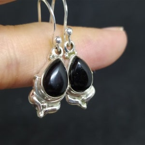 May include: A pair of silver dangle earrings with black teardrop-shaped stones.