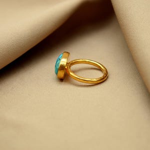 May include: A gold ring with a turquoise gemstone. The ring has a hammered texture.