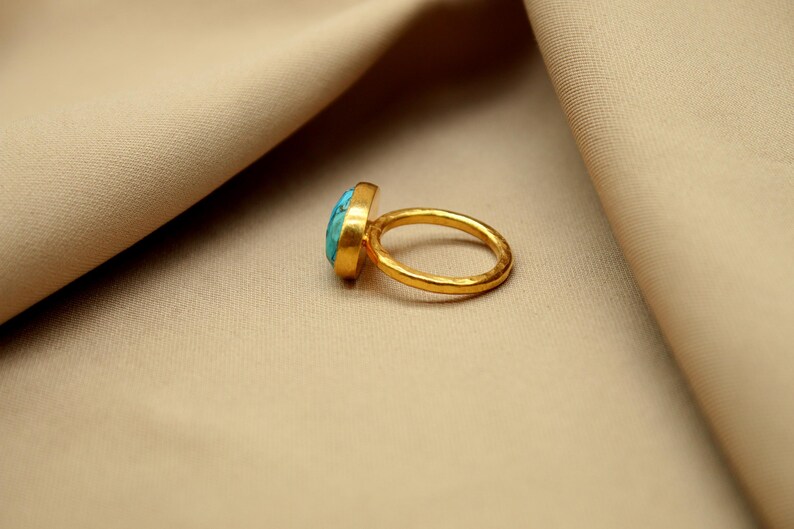 May include: A gold ring with a turquoise gemstone. The ring has a hammered texture.