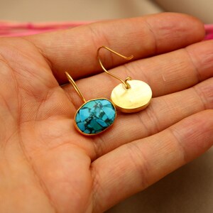 May include: A pair of gold earrings with turquoise stones. The earrings are oval shaped and have a simple design.
