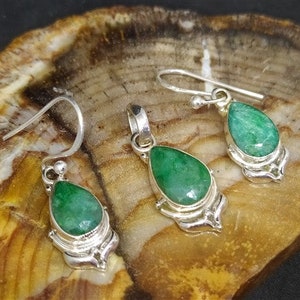 Pu&ograve; includere: Un set di gioielli con un ciondolo e orecchini abbinati. Ogni pezzo ha una pietra preziosa verde sfaccettata a forma di goccia incastonata in metallo color argento. Gli orecchini hanno un design a gancio e il ciondolo ha un anello per una catena.
