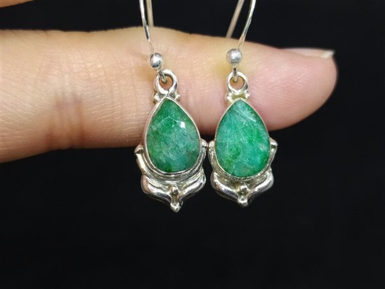 Pu&ograve; includere: Un paio di orecchini in argento con pietre preziose verdi a forma di goccia. Gli orecchini hanno una montatura in argento dettagliata con elementi decorativi. Le pietre preziose sono di un ricco colore verde smeraldo.