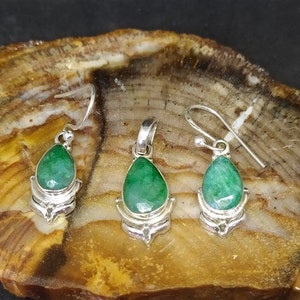 Pu&ograve; includere: Un set di gioielli con un ciondolo e due orecchini. Ogni pezzo ha una gemma verde a forma di goccia, incastonata in metallo color argento. Gli orecchini hanno chiusure a gancio e il ciondolo ha un anello per una catena.