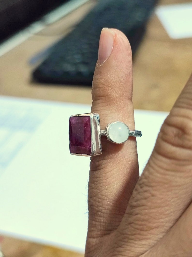 K&ouml;nnte beinhalten: Ein silberner Ring mit einem gro&szlig;en, rechteckigen, dunkelroten Edelstein und einem kleineren, runden, wei&szlig;en Edelstein.