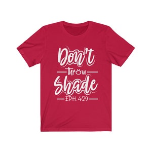 May include: Red short-sleeved t-shirt with white text that reads "Don't throw shade - EPH. 4:29 -"