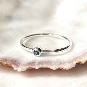 Peut inclure: Une bague simple en argent avec un petit saphir bleu rond.