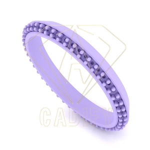 Puede incluir: Un anillo de silicona lavanda con un borde texturizado y con cuentas.
