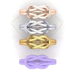 K&ouml;nnte beinhalten: Vier Infinity-Knotenringe in verschiedenen Farben. Der oberste Ring ist ros&eacute;gold, der zweite silber, der dritte gold und der unterste lila.