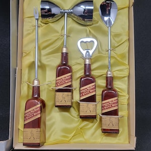 May include: A set of five silver bar tools in a yellow box. The tools include a cocktail shaker, a bottle opener, a jigger, and two long spoons. The box also contains four miniature bottles of Johnnie Walker Scotch Whisky.