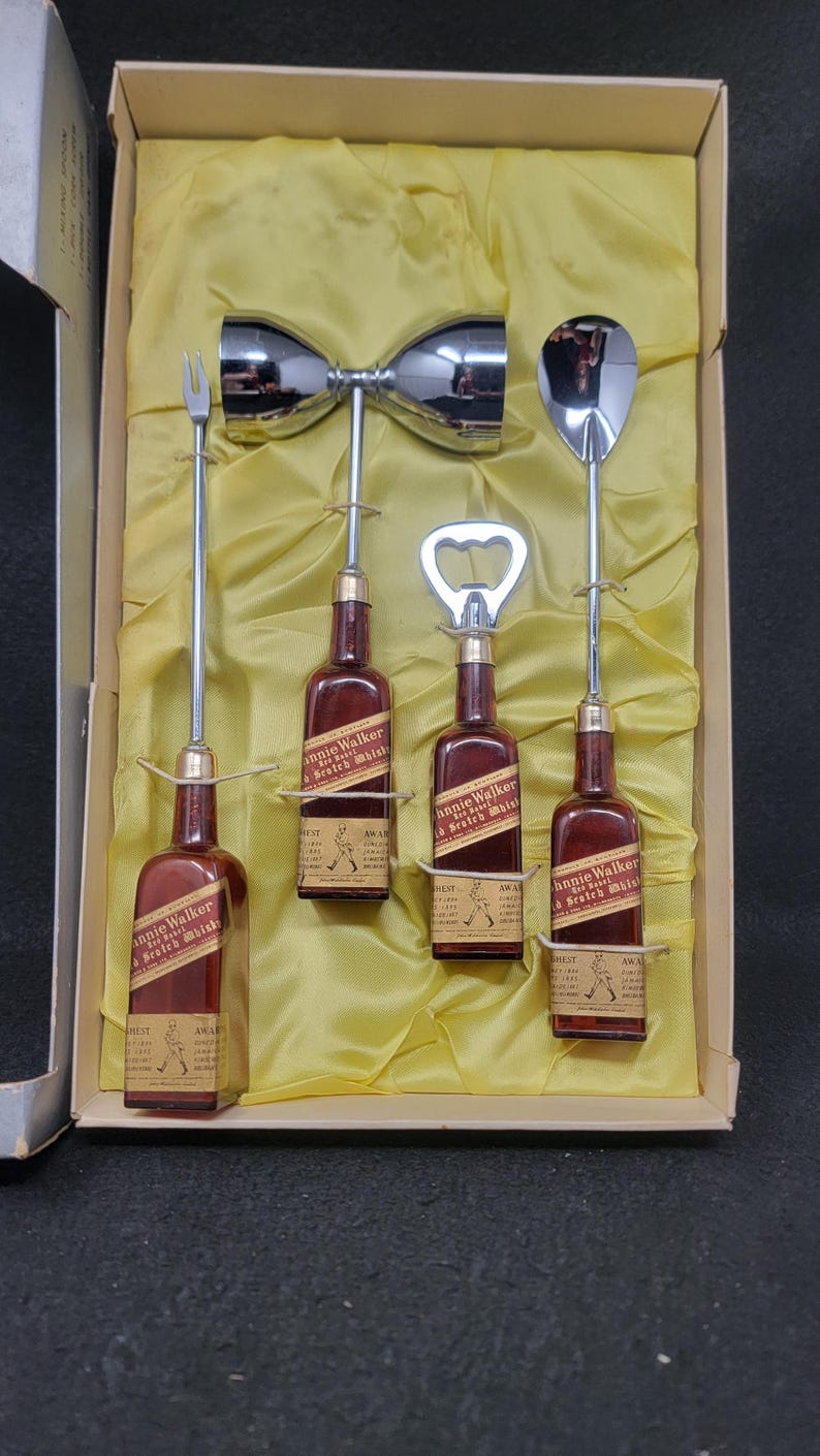 May include: A set of five silver bar tools in a yellow box. The tools include a cocktail shaker, a bottle opener, a jigger, and two long spoons. The box also contains four miniature bottles of Johnnie Walker Scotch Whisky.