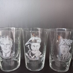 May include: Four clear glass tumblers with etched portraits of historical figures. The glasses feature the names "ROOSEVELT", "MONTGOMERY", "DE GAULLE", and an unreadable name.