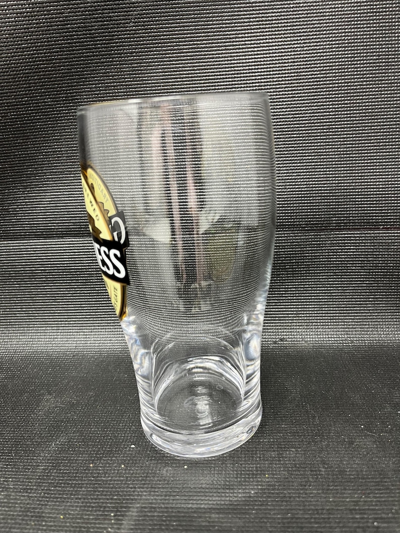 May include: A white ceramic mug with a black handle and the text "But first, coffee" in a handwritten style. The mug is on a white surface. The mug is approximately 4 inches tall.