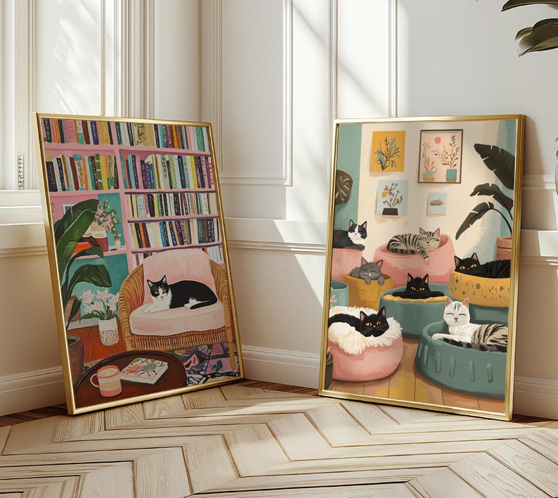 May include: Two framed art prints with gold frames. One depicts a cat in a pink chair in front of a bookshelf. The other shows several cats lounging in various beds. The artwork has a cozy, inviting feel.
