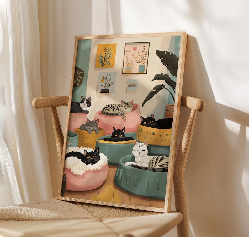 May include: A framed art print featuring a whimsical illustration of several cats lounging in colorful beds. The cats have various markings, including black, gray, and tabby patterns. The artwork is set against a light background with decorative plants.