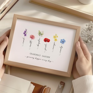 May include: A framed print with a watercolor illustration of flowers and names. The text reads "Grandma's Garden - growing bigger every day".