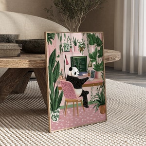Op de afbeelding: Een ingelijste illustratie van een pandabeer die aan een bureau zit met een computer, omringd door planten. De panda draagt een zwart-witte vacht en heeft een roze stoel. Het computerscherm toont code.