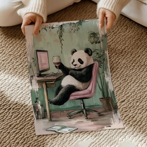 May include: A panda bear sitting in a pink chair, wearing a black and white fur coat, holding a glass of red wine and looking at a computer screen. The panda is in a room with green plants and a wooden desk.