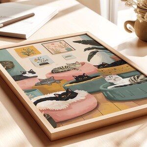 May include: A framed art print featuring a whimsical illustration of cats lounging in colorful beds. The artwork showcases various cat breeds, including black, gray, and tabby cats, in a cozy indoor setting. The print is set in a light wood frame.
