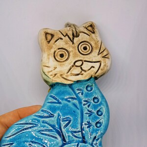 May include: A ceramic cat figurine with a blue and white glaze. The cat has a whimsical expression and is decorated with a floral pattern.