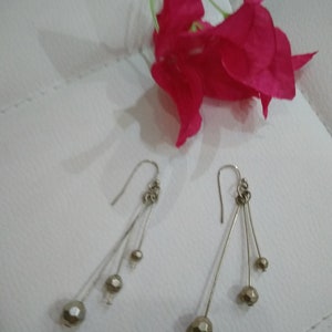 以下が含まれることがあります： 3つの丸いファセットカットビーズがついた、シルバーのドロップイヤリングのペア