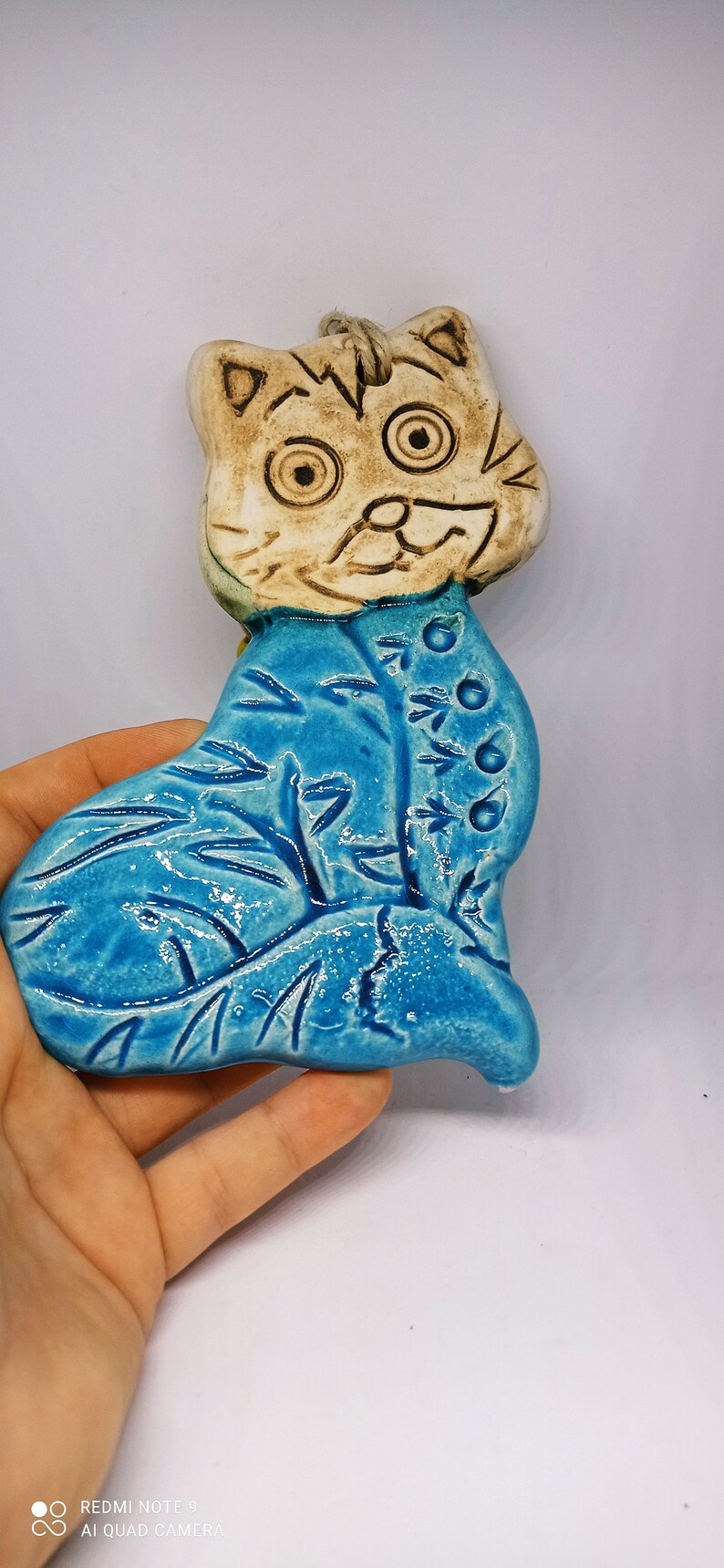 May include: A ceramic cat figurine with a blue and white glaze. The cat has a whimsical expression and is decorated with a floral pattern.