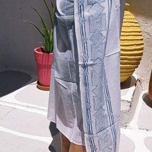 May include: A white sarong with a blue geometric pattern. The sarong is tied around the waist and the pattern is visible on the side.