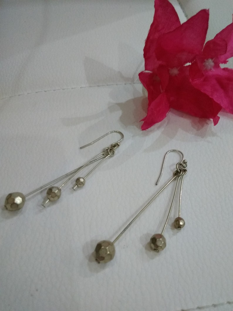 以下が含まれることがあります： 銀製のドロップイヤリングのペア。各イヤリングには、小さなファセットカットのゴールドトーンのビーズが3つ付いています。
