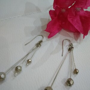 以下が含まれることがあります： 3つの丸いファセットカットビーズがついた、シルバーのドロップイヤリングのペアです。