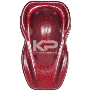 May include: A red glitter paint sample with a textured finish. The sample is shaped like a car hood and has the text "KP Pigments" printed on it.